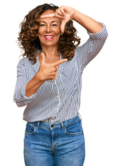 Middle age hispanic woman wearing casual clothes smiling making frame with hands and fingers with happy face. creativity and photography concept.
