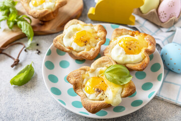 Easter breakfast idea. Scrambled eggs in puff pastry with cheese and bacon on a stone background.