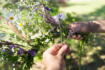 Making a Festive flower wreath,  circlet of flowers, making coronet of flowers on a bright sunny afternoon. Preparing for Midsummer night fest. How to Make a Flower Crown. Festival flower crown.