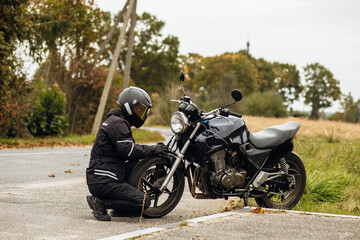 motorcyclist in motorcycle clothing and a helmet on an old motorcycle cafe racer in the summer on...