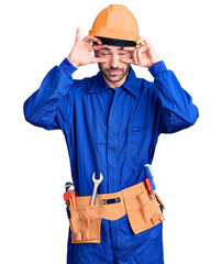 Young hispanic man wearing worker uniform trying to open eyes with fingers, sleepy and tired for morning fatigue