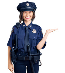 Young beautiful girl wearing police uniform smiling cheerful presenting and pointing with palm of hand looking at the camera.