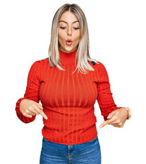 Beautiful blonde woman wearing casual clothes pointing down with fingers showing advertisement, surprised face and open mouth © Krakenimages.com