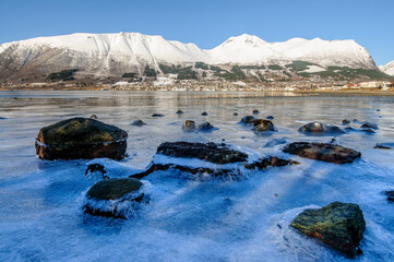 frozen sea with rocks sticking out of the ice with ørsta and nivane