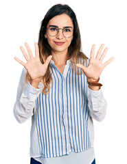 Beautiful hispanic woman wearing casual striped shirt showing and pointing up with fingers number ten while smiling confident and happy.