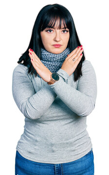 Young hispanic plus size woman wearing winter scarf rejection expression crossing arms doing negative sign, angry face