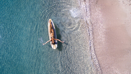 Donna sdraiata su tavola da surf galleggia sul mare