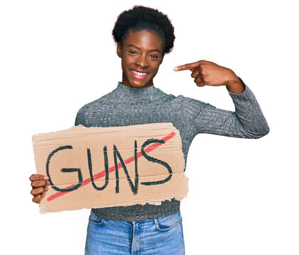 Young african american girl holding no guns warning banner pointing finger to one self smiling happy and proud