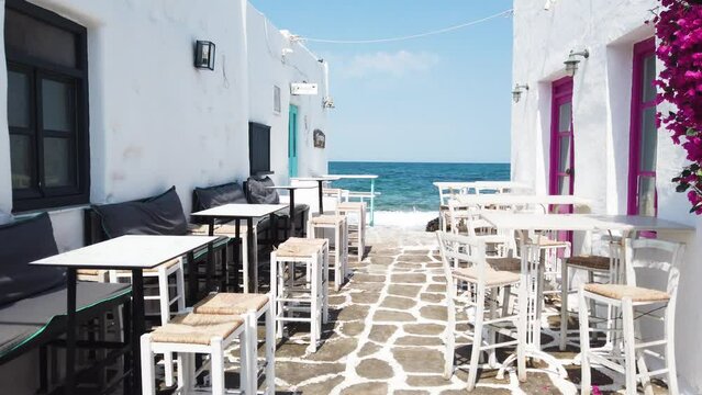 Naoussa typical white street leading to sea with sunshine, small village on Paros island, Greece