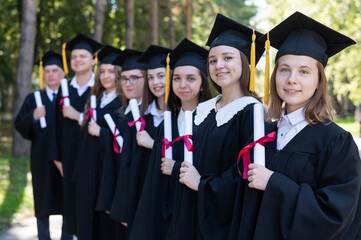 Row of young people in graduation gowns outdoors. Age student.