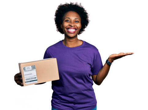 African american woman with afro hair holding delivery package celebrating achievement with happy smile and winner expression with raised hand