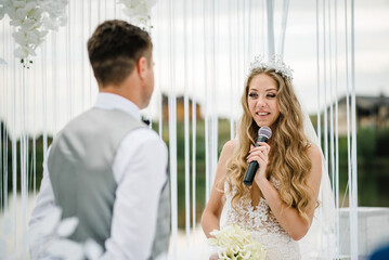 Happy young bride and groom exchanging wedding vows on ceremony. The bride says the promise in the...