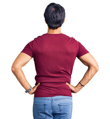 Handsome hispanic man wearing casual clothes standing backwards looking away with arms on body