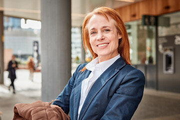 Successful middle-aged businesswoman smiling in front of luxury office.