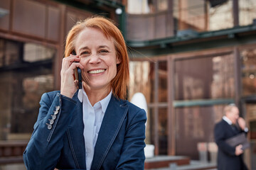 Ambitious middle-aged businesswoman, embracing unexpected challenges with a determined and professional attitude talking on mobile phone