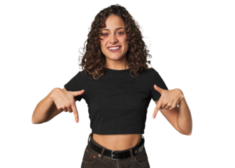 Radiant young woman with stunning curls points down with fingers, positive feeling.