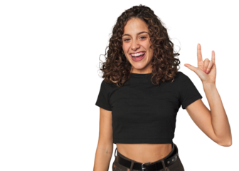 Radiant young woman with stunning curls showing a horns gesture as a revolution concept.
