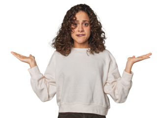 Radiant young woman with stunning curls confused and doubtful shrugging shoulders to hold a copy space.