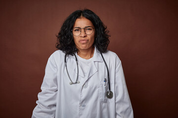 Young colombian doctor woman with stethoscope shrugs shoulders and open eyes confused.