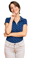 Young brunette woman with short hair wearing casual clothes looking confident at the camera with smile with crossed arms and hand raised on chin. thinking positive.