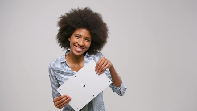 Overjoyed dancing afro american curly woman holding a placard with grey space.