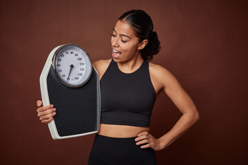 Young fitness woman measuring progress with a scale for healthy living.
