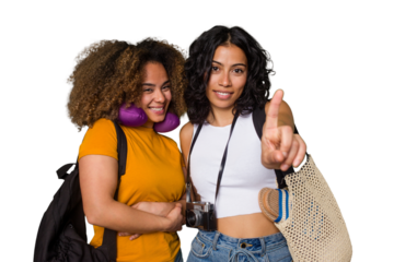 Two diverse friends on a beach vacation with vintage camera, beach bag, and travel pillow showing number one with finger.