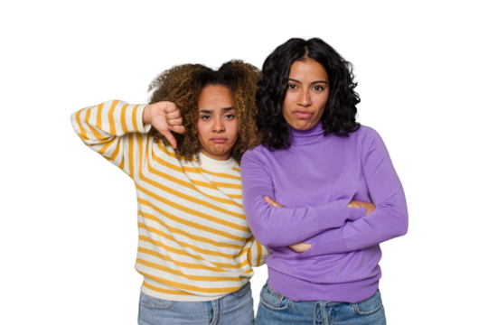 Two female friends isolated in studio showing a dislike gesture, thumbs down. Disagreement concept. - Powered by Adobe