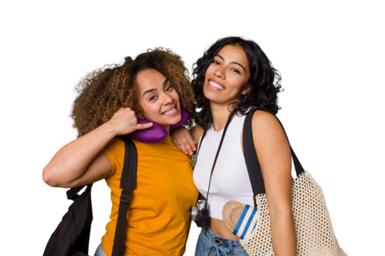 Two diverse friends on a beach vacation with vintage camera, beach bag, and travel pillow showing a mobile phone call gesture with fingers.