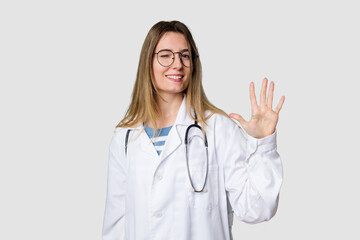 Compassionate female physician with a stethoscope around her neck, ready to diagnose and care for her patients in her signature white coat smiling cheerful showing number five with fingers.