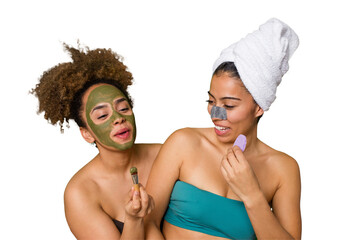 Two friends pamper themselves with facial treatments for a relaxing spa day at home, with laughter...