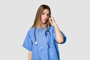 Young female nurse in uniform with stethoscope, symbol of care and dedication to patients raising fist after a victory, winner concept.