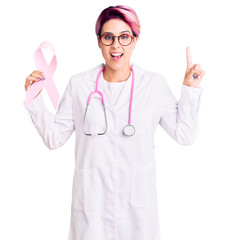 Young beautiful woman with pink hair wearing doctor stethoscope holding cancer ribbon surprised with an idea or question pointing finger with happy face, number one