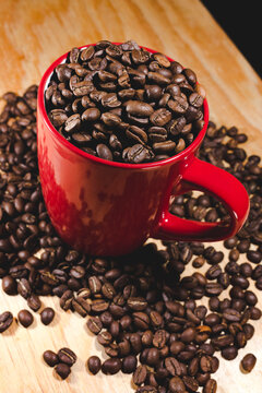 Photography Of Red Cup Full Of Coffee Beans On Wooden Table