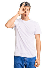 Fototapeta premium Young handsome man wearing casual white tshirt doing ok gesture shocked with surprised face, eye looking through fingers. unbelieving expression.