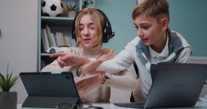 Jojful children sitting the table play online video games and browsing social media in their room at home