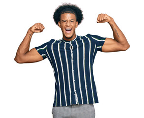 Fototapeta premium African american man with afro hair wearing casual clothes showing arms muscles smiling proud. fitness concept.