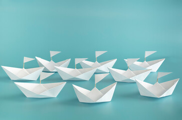 White paper ships on blue background with white flags indicate direction, unity, competition, goals, team group concept.