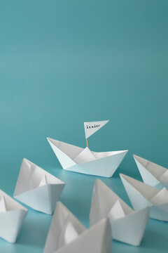 Leadership, teamwork and courage concept. White paper boats on blue background.