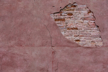 Opening on a wall of a house in Venice. You can see the bricks and the details of the wall. Pink and highly detailed texture.