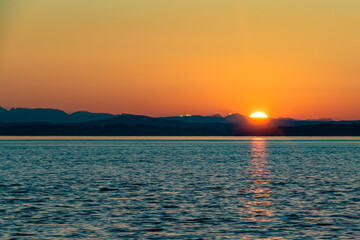 Sun Setting Over Horizon and Mountains Along Coast of Strait of Georgia in Vancouver Island , British Columbia, Canada