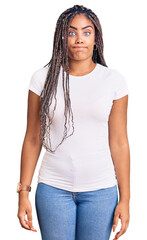 Obraz premium Young african american woman with braids wearing casual clothes puffing cheeks with funny face. mouth inflated with air, crazy expression.