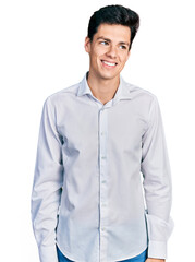 Young hispanic business man wearing business clothes looking away to side with smile on face, natural expression. laughing confident.