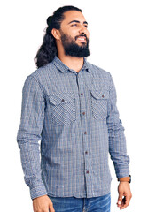 Young arab man wearing casual clothes looking away to side with smile on face, natural expression. laughing confident.