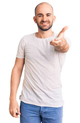 Young handsome man wearing casual t shirt smiling friendly offering handshake as greeting and welcoming. successful business.