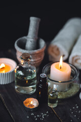 Spa setting with essential oil, candle, sea salt, pebbles, towel on dark wooden background. Massage, aromatherapy. Natural organic ingredients for relaxation, detention. Wellness in salon concept