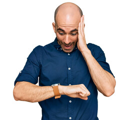 Young hispanic man wearing casual clothes looking at the watch time worried, afraid of getting late