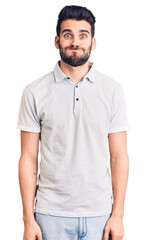 Young handsome man with beard wearing casual polo puffing cheeks with funny face. mouth inflated with air, crazy expression.