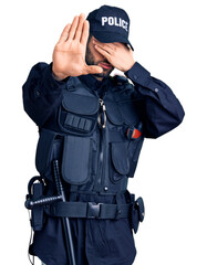 Young handsome man with beard wearing police uniform covering eyes with hands and doing stop gesture with sad and fear expression. embarrassed and negative concept.
