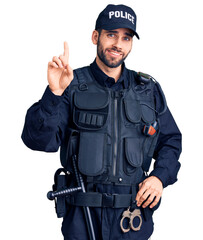 Young handsome man with beard wearing police uniform showing and pointing up with finger number one while smiling confident and happy.